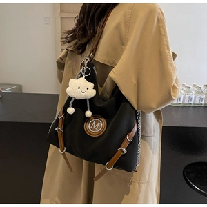 Détail du sac cabas en nylon noir avec bordure en cuir marron et logo M et chaîne