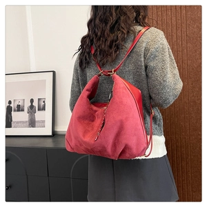 Macro detail of red frosted suede tote bag with golden hardware shown on a shoulder
