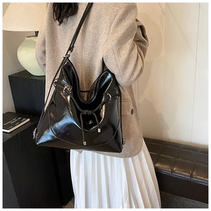Detail of glossy black large tote bag showing side drawstring and metallic accents