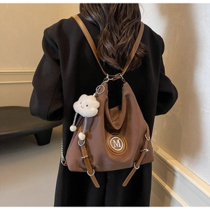 Détail d'un sac à dos fourre-tout marron foncé avec lanières en cuir et porte-clés nuage