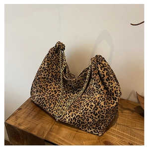 Detail of leopard print tote bag with double gold chains on a wooden surface