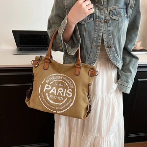 Sac fourre-tout vintage en toile marron avec anses en cuir porté par un mannequin