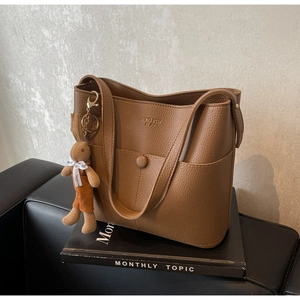 Macro detail of dark brown pebble leather tote bag with creative rabbit charm accessory