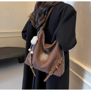 Détail d'un grand sac cabas marron avec logo M en métal et pendentif nuage en peluche