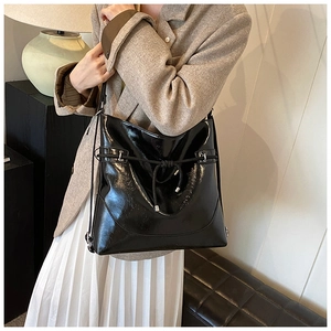 Detail view of the black glossy leather bag with elegant knot decoration and silver buckle