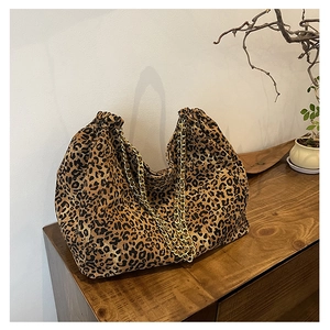 Detail of leopard print tote bag with golden chain straps on a wooden surface