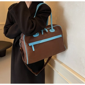 Seitenansicht der großen braunen Nylon-Reisetasche mit blauen Paspeln an einem Modell
