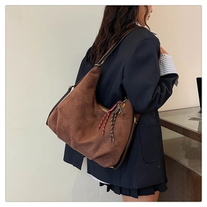 Detail view of brown suede Hobo bag with stylish braided rope charm and leather strap