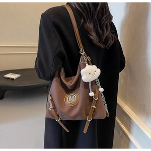 Détail latéral du grand sac cabas marron avec logo M en métal et breloque nuage peluche