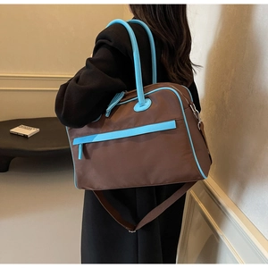 Große Reisetasche aus Nylon mit blauen Lederriemen und verstellbarem Schultergurt im Detail