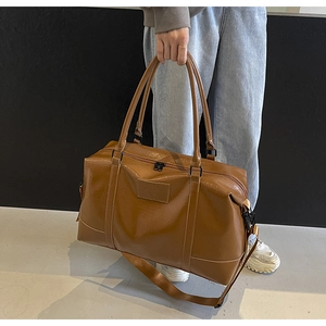 Close-up of large brown leather travel bag with lychee texture and adjustable shoulder strap