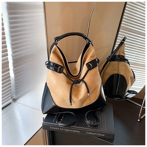 Detail of khaki suede hobo bag with black leather trim and drawstring in soft lighting
