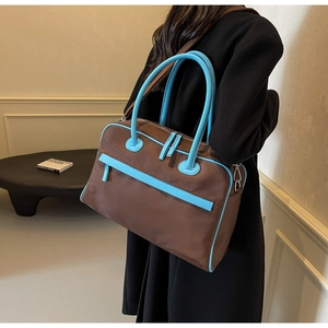 Details zur großen braunen Reisetasche mit kontrastierenden blauen Griffen und Besätzen