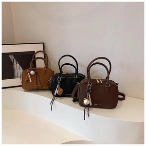 Dettaglio borse a bauletto vintage in marrone, nero e caffè con ciondoli sportivi