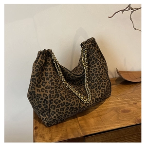 Detail of leopard print tote bag with gold chain strap on a wooden surface