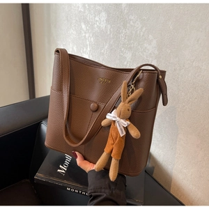 Detail of dark brown litchi grain leather tote bag featuring a cute rabbit plush pendant