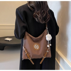 Détail d'un grand sac cabas marron en nylon avec logo M et pendentif nuage en peluche