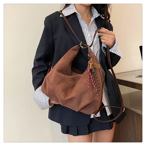 Detail of dark brown faux suede crossbody bag with decorative key pendant and adjustable strap