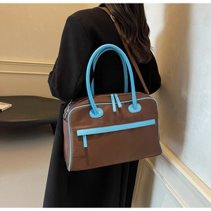 Detailansicht der braunen Damen-Tragetasche mit blauem Besatz an einem Modell im schwarzen Mantel