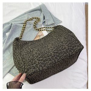 Detail of leopard print tote bag with golden chain strap on casual denim jacket background