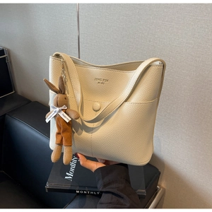 Detail of off-white lychee grain leather bucket bag with a cute rabbit plush pendant