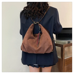 Detailed back view of a brown suede hobo backpack with woven rope pendant detail