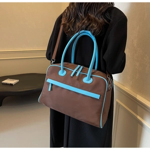 Detail einer großen braunen und himmelblauen Reisetasche, von einem Modell getragen