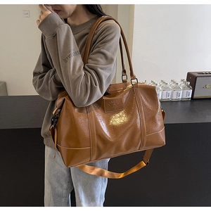 Brown gloss leather travel bag detail showing the embossed Vanessa Fashion logo plate