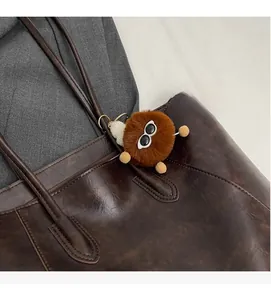 Detail eines braunen Webpelz-Anhängers mit Sonnenbrille an einer Leder-Tragetasche