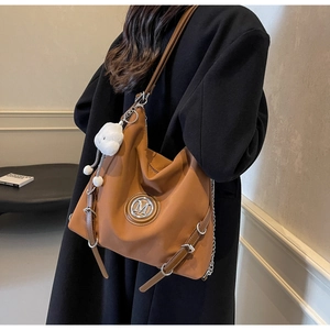 Grand sac cabas marron avec logo M argenté et breloque mouton en peluche sur manteau noir