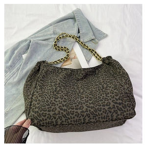 Detail of leopard print tote bag featuring a gold chain strap and textured fabric finish