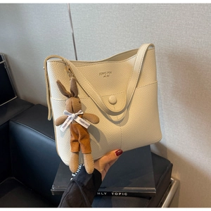 Detail of off-white lychee leather bucket bag with cute brown knit rabbit charm