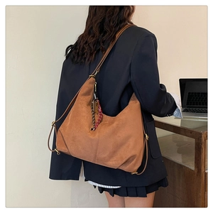 Detail of a brown suede tote bag featuring a bicolor woven lanyard and slim shoulder strap
