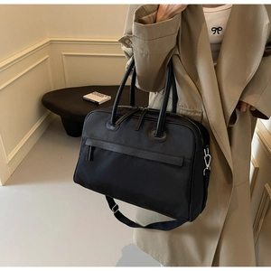 Detail einer großen schwarzen Reisetasche aus strapazierfähigem Stoff mit Ledergriffen