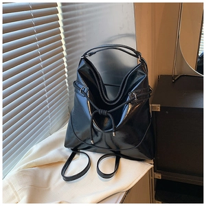 Detail of high-shine black leather tote bag with drawstring closure and glossy finish