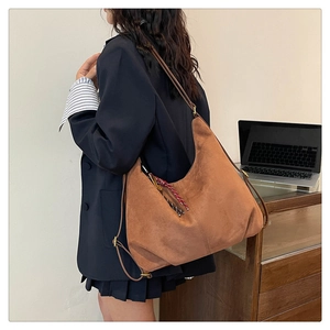 Detail of a brown matte faux suede convertible backpack tote bag on a model's shoulder