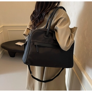 Rückansicht eines Models mit großer schwarzer Reisetasche und verstellbarem Schultergurt