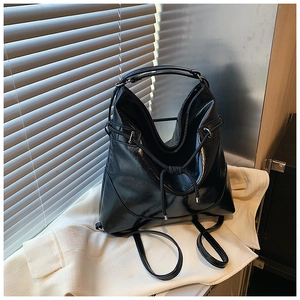 Detail of glossy black drawstring bag placed on white suit with elegant lighting