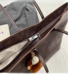 Detail des silbernen Reißverschlusses und Fischgrätenfutters an der braunen Shopper-Tasche