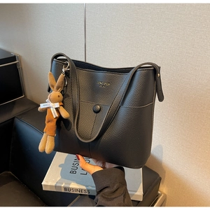 Detail of black lychee grain leather bucket bag with gold logo and rabbit charm