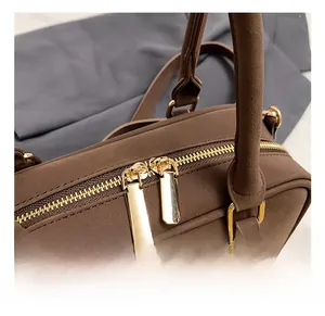 Dettaglio della ferramenta dorata e delle doppie zip su borsa marrone in scamosciato