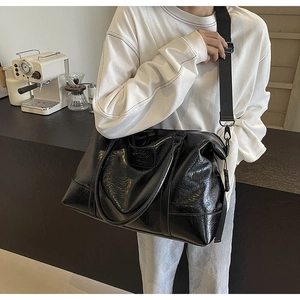 Close-up of black quilted faux leather travel bag with adjustable strap and embossed logo