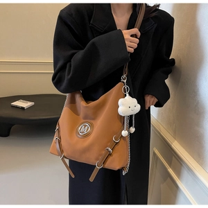 Détail du sac cabas marron avec logo M en métal, breloque nuage et bandoulière