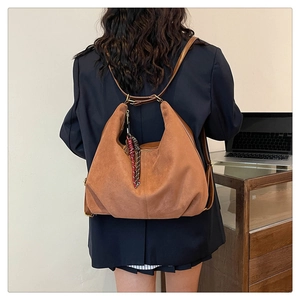 Detail of a brown frosted suede hobo bag with a woven charm in an office setting