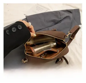 Dettaglio borsa a tracolla in pelle marrone scuro con interno spazioso e tasche zip