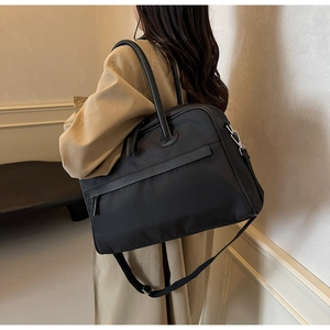 Detail einer großen schwarzen Nylon-Reisetasche, die als Umhängetasche getragen wird