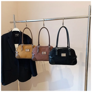 Tre borse Boston in giallo, marrone e nero in materiale opaco appese al rack