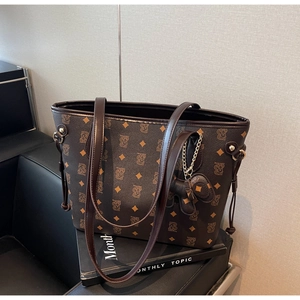 Détail du sac cabas marron foncé avec motif monogramme B et charmant pendentif d'ours