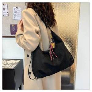 Close-up of black matte suede tote bag featuring braided cord and key pendant detail