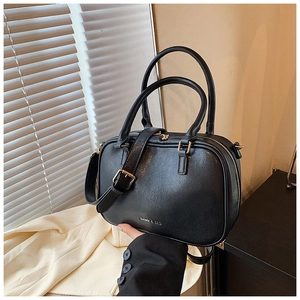 Dettaglio borsa a cuscino in pelle nera con cerniere dorate e marchio DAIMU & BAG